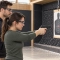 Kobieta w okularach ochronnych celuje pistoletem airsoft w tarczę w obecności mężczyzny